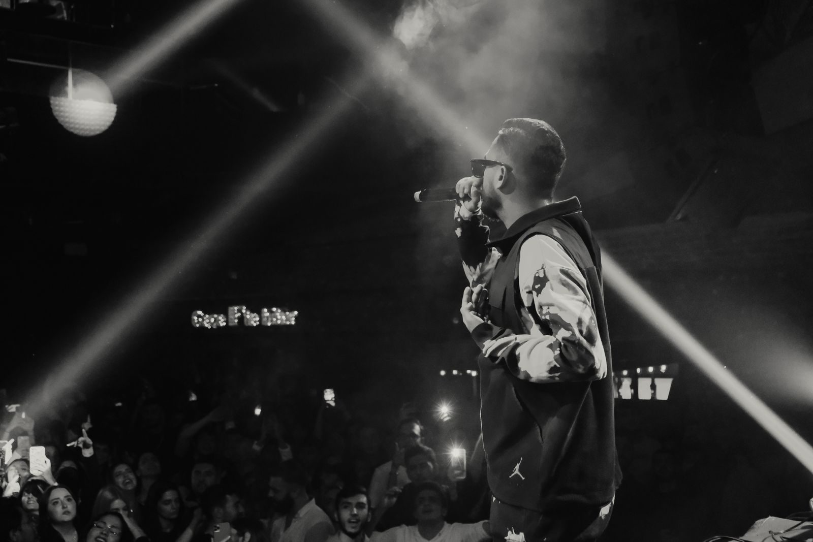 Headline performer on stage under spotlights facing a packed crowd