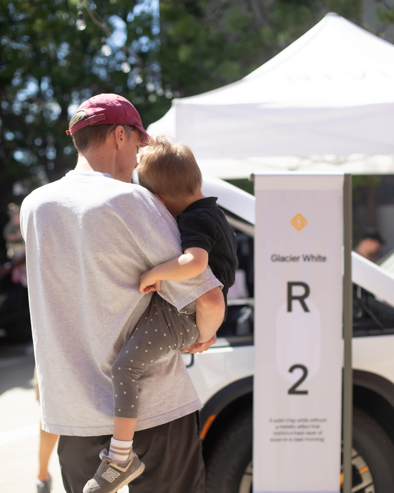 Family exploring the Rivian R2 Glacier White display at the block party