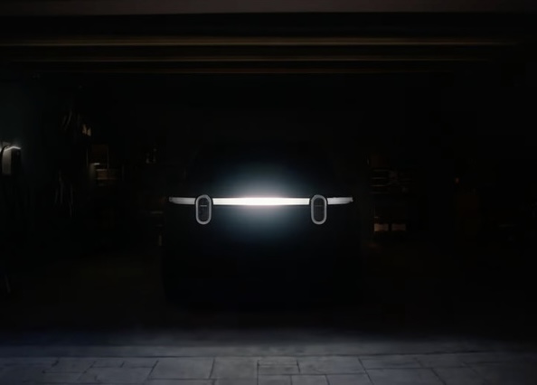 Rivian R2 electric SUV front light bar glowing in a dark garage