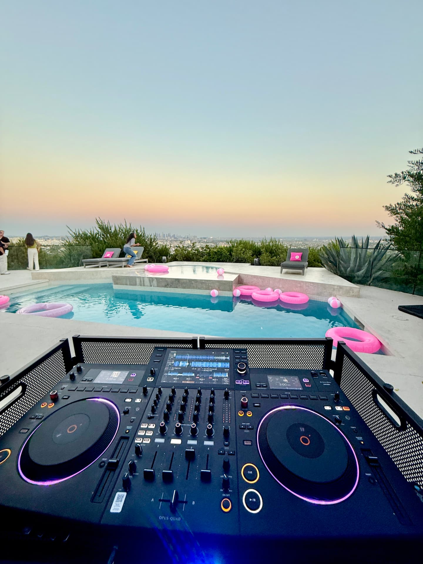 DJ controller overlooking a rooftop pool at sunset